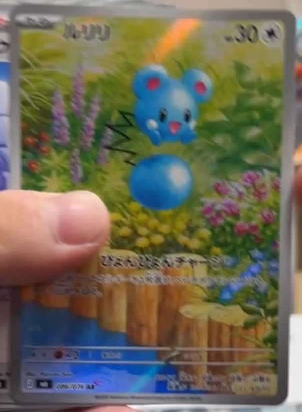 Leaked Azurill Illustration Rare from Storm Emerald, showing Azurill bouncing on its tail in a wildflower meadow beside a stream