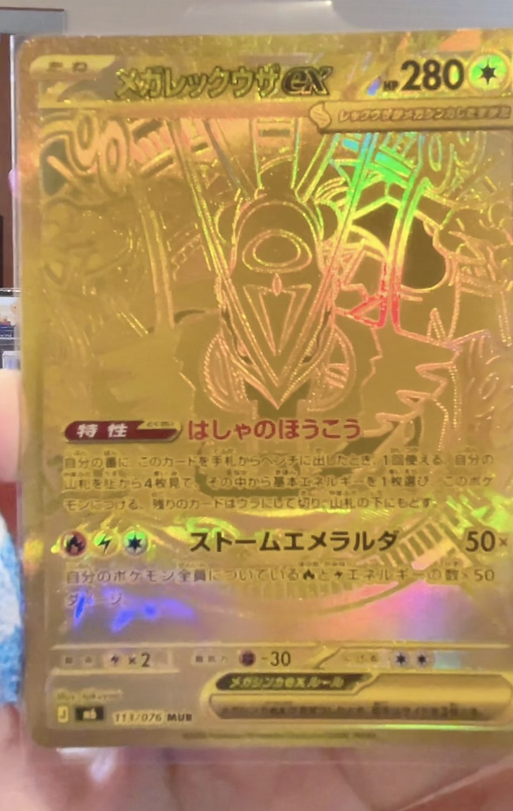 Leaked gold Mega Rayquaza ex from Storm Emerald, numbered 111/076 MUR, with the card face embossed entirely in gold foil